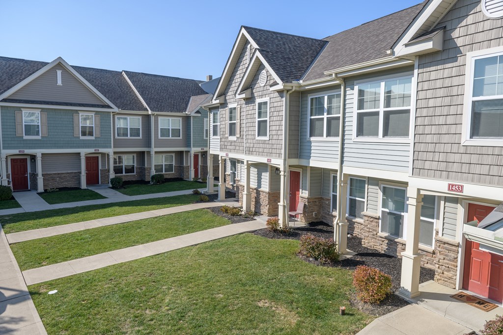 a row of houses with a grass yard and sidewalk