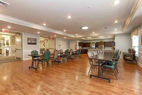a community room with tables and chairs and a kitchen