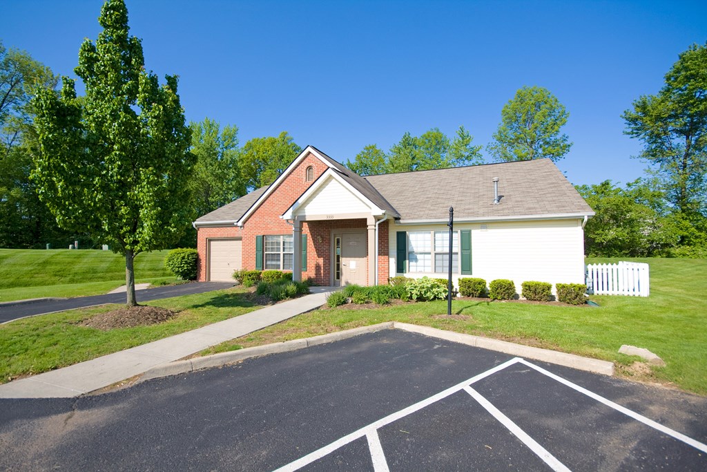 a small house with a driveway and lawn in front of it