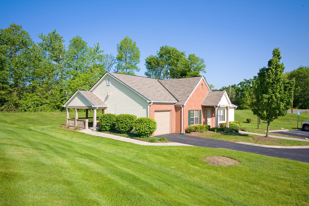 a house on the corner of a street with a lawn and trees