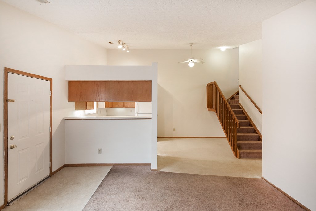 an empty living room with a kitchen and stairs in a house