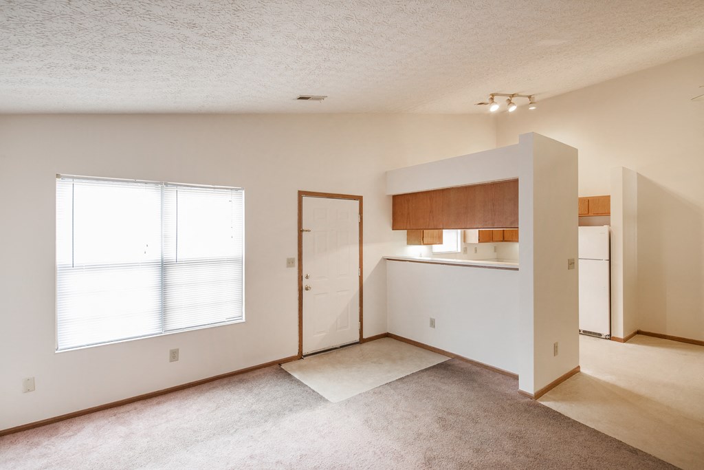 an empty living room and kitchen with a door to the bathroom
