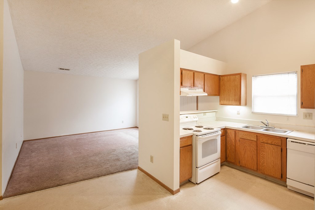 an empty kitchen with white appliances and wooden cabinets