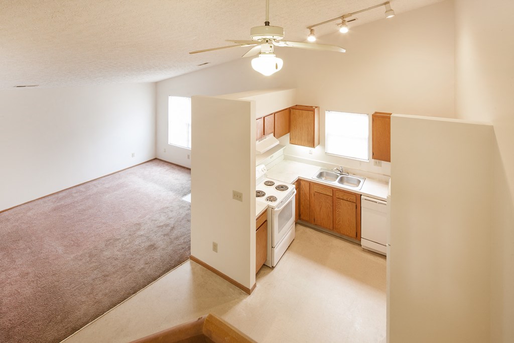 an empty kitchen and living room with a ceiling fan