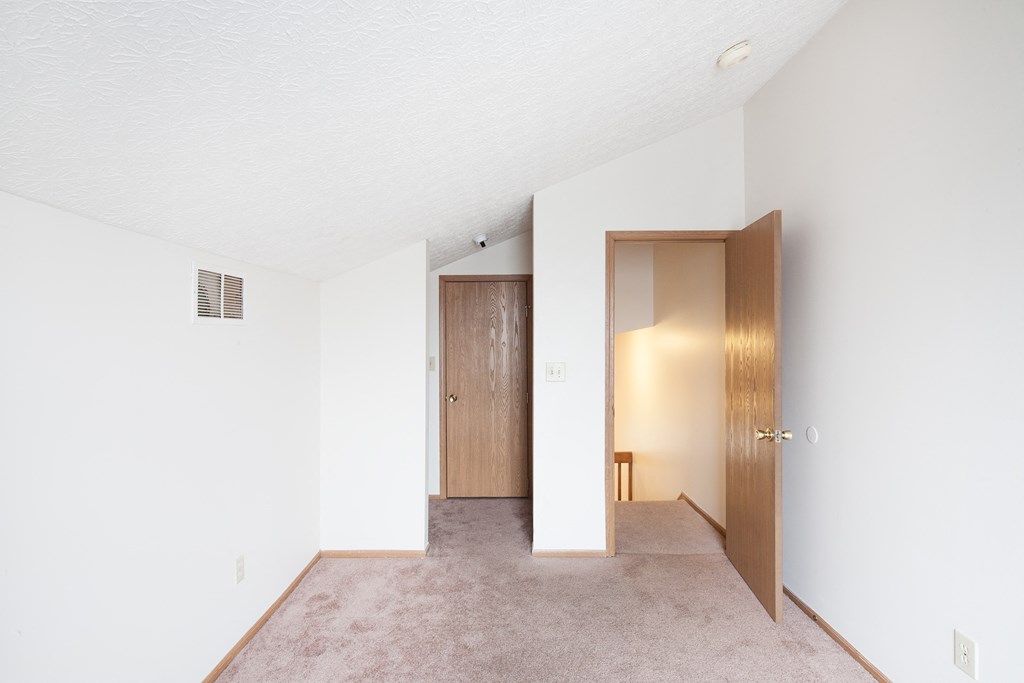 an empty living room and hallway with a door to a closet