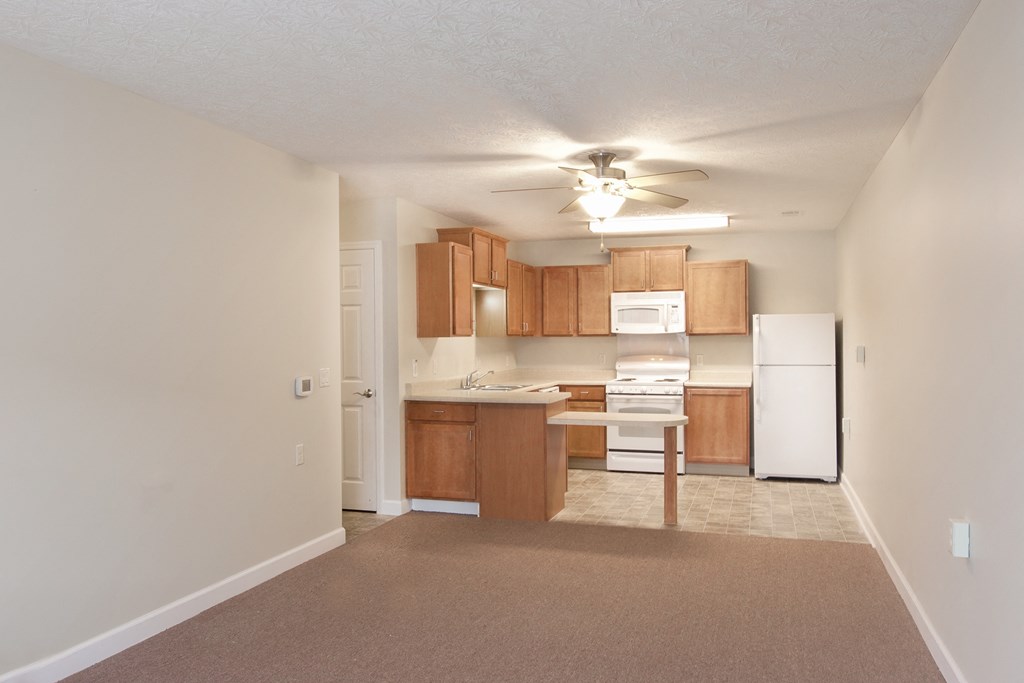 an empty living room and kitchen with a ceiling fan