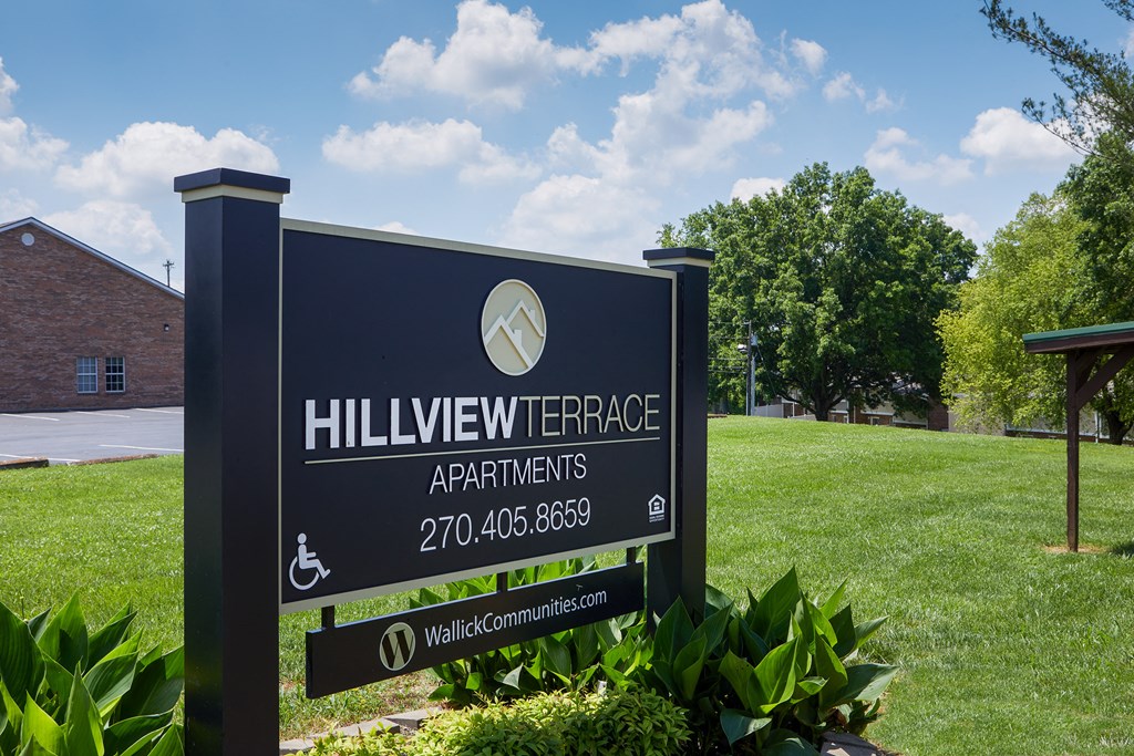 a sign for hillview terrace apartments in front of a lawn and trees