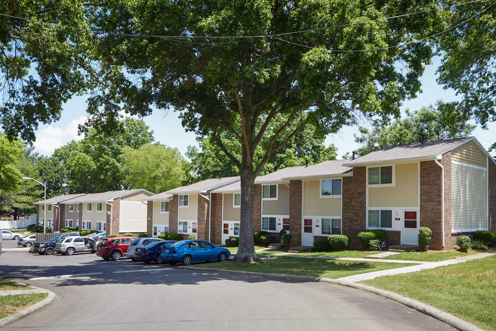a row of apartment buildings with cars parked in front