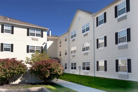 an exterior view of an apartment building with a sidewalk and grass