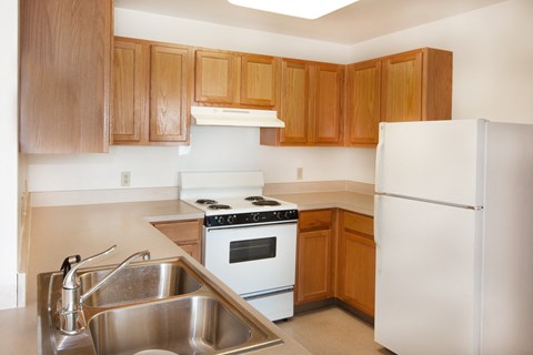 a kitchen with white appliances and wooden cabinets and a sink