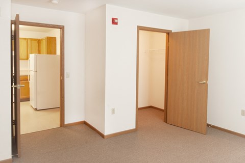 a bedroom with a door to a bathroom and a refrigerator