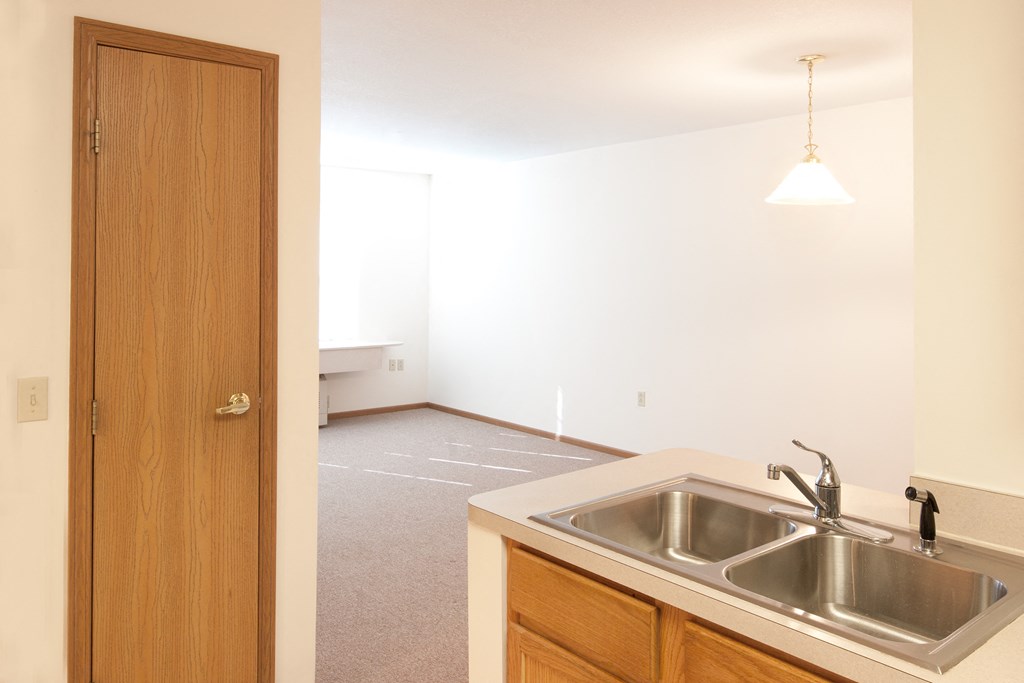 a kitchen with a sink and a door into a living room