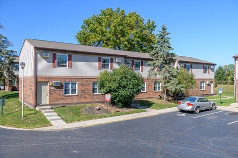 an apartment building with a car parked in a parking lot