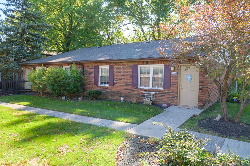 a small brick house with a sidewalk in front of it