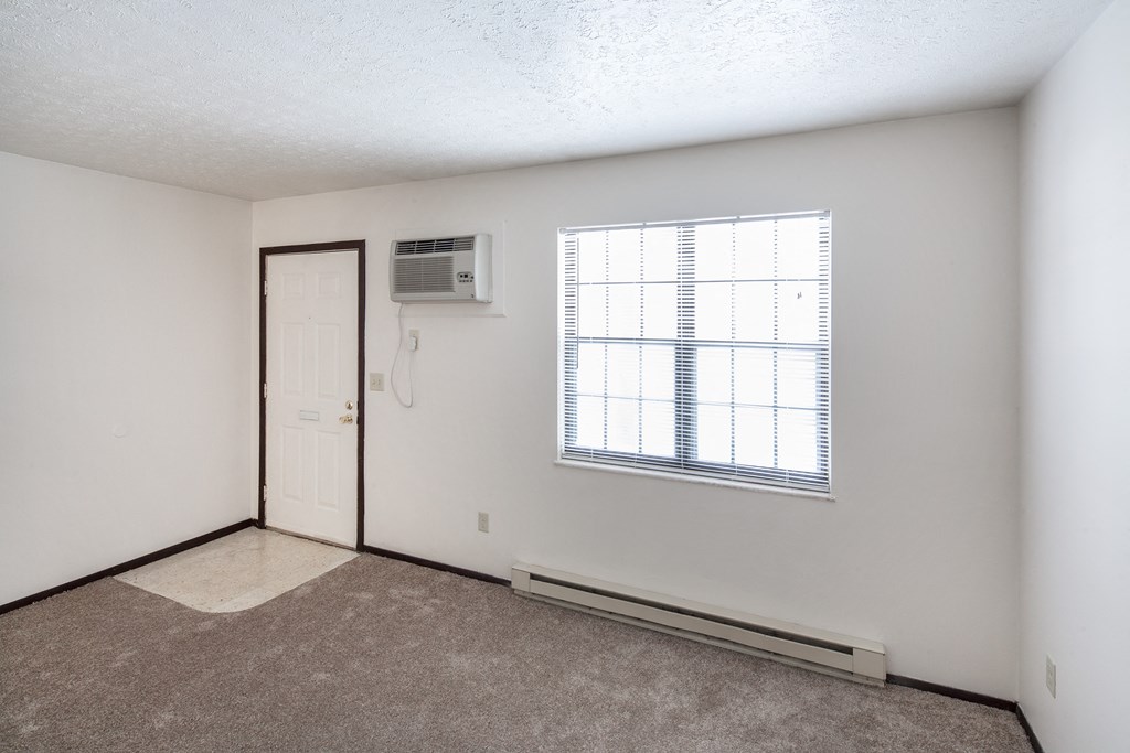 the living room of an apartment with a window and a door