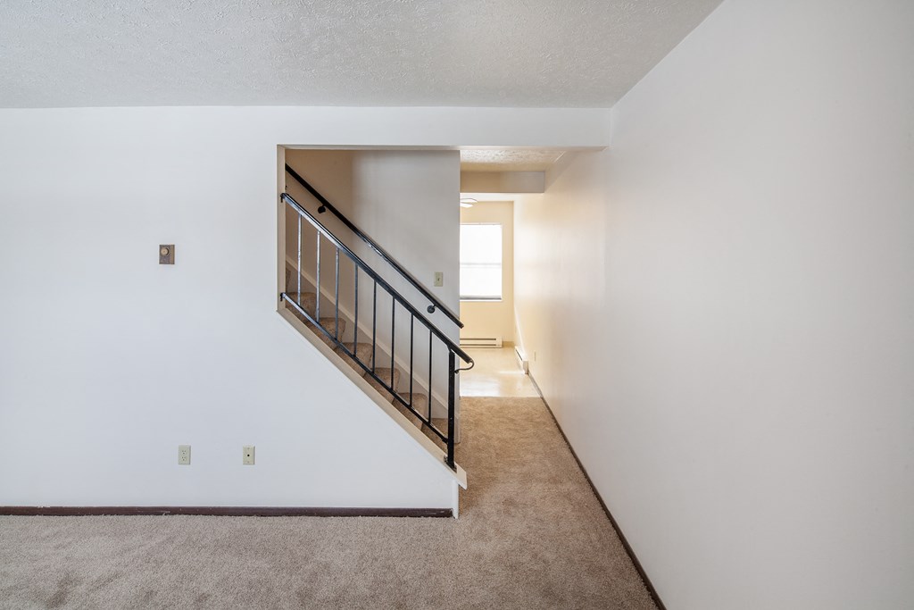 the upstairs of a home with a staircase and a carpeted floor