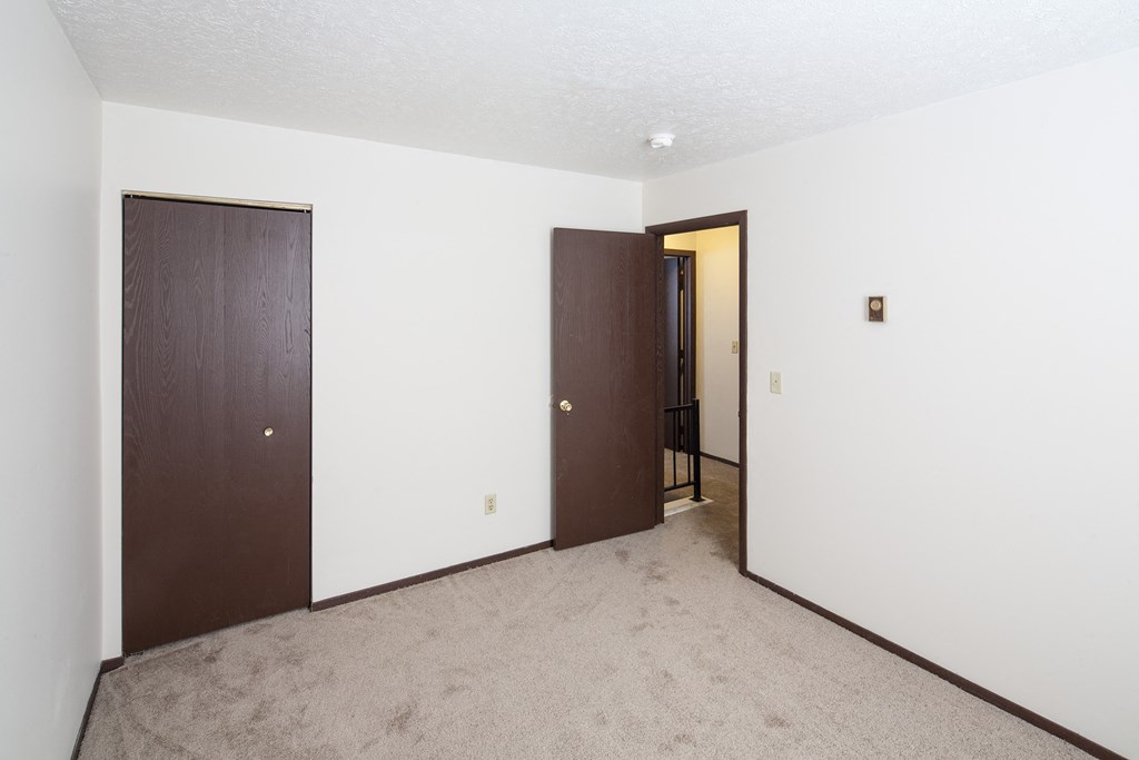 an empty living room with a door to a hallway and a closet