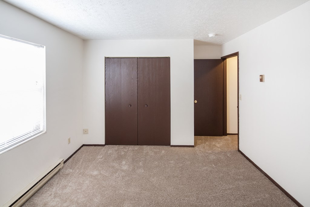 an empty room with a closet and a window