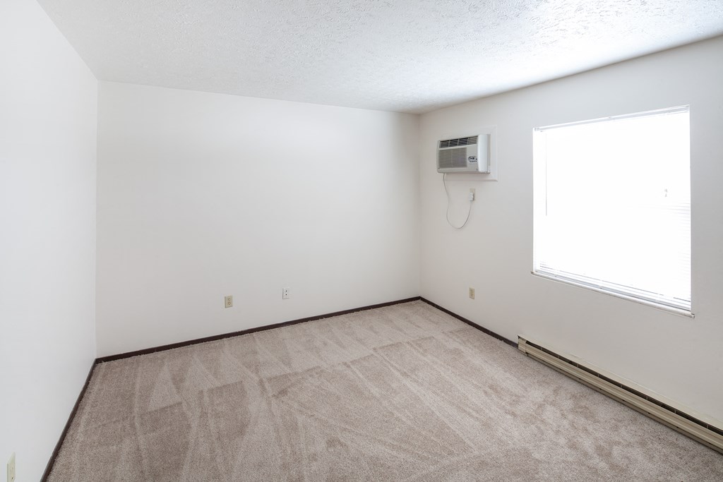 the living room of an empty apartment with a heater and a window