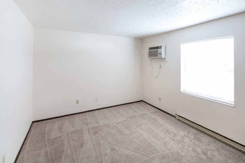 the living room of an empty apartment with a heater and a window