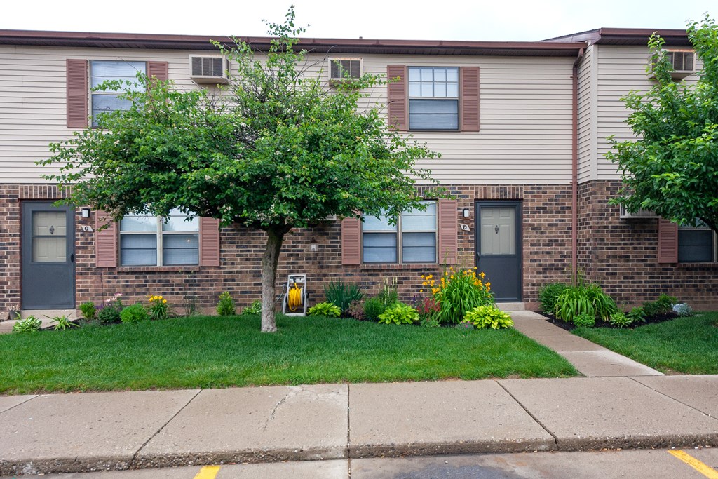 the front of a brick house with a tree in the yard