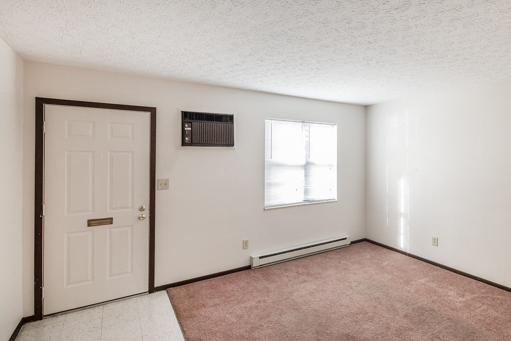 an empty living room with a white door and a window