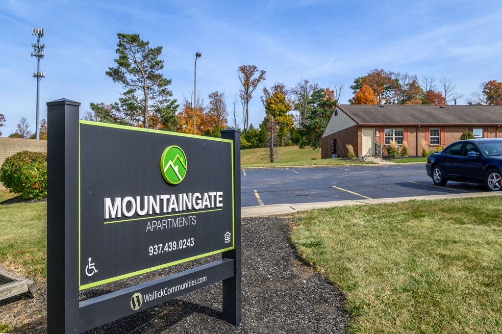 a sign that reads mountaingate apartments in front of a parking lot