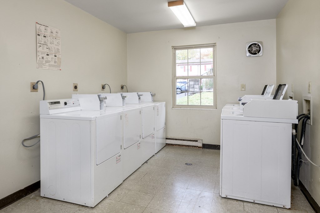 an empty laundry room with white washers and dryers in it