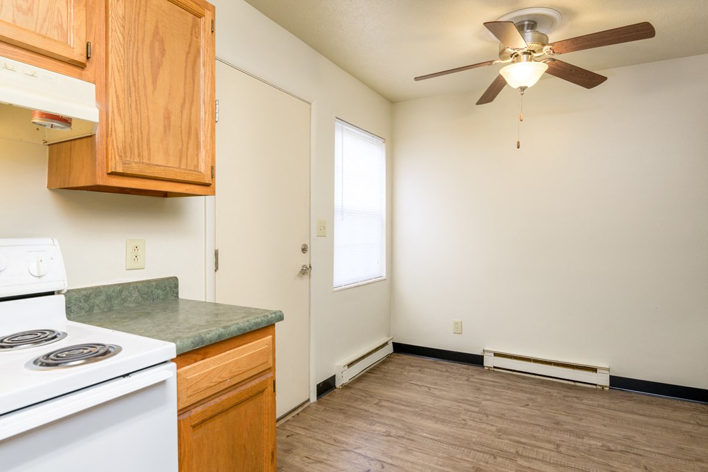 an empty kitchen with a stove and a ceiling fan
