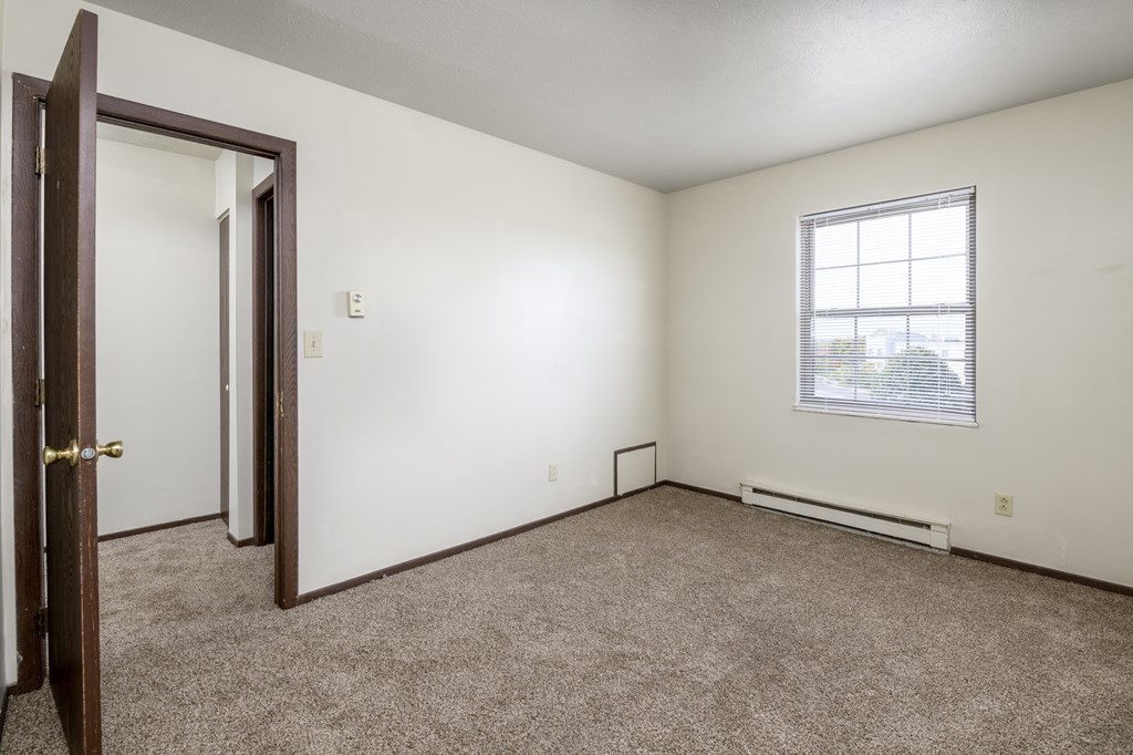the living room of an empty home with carpet and a window