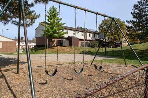 a swing set in a playground with a house in the background