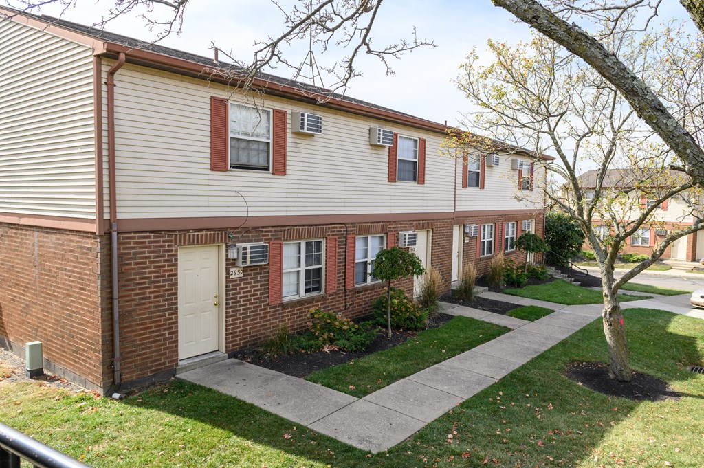 a white and brick house with a sidewalk in front of it