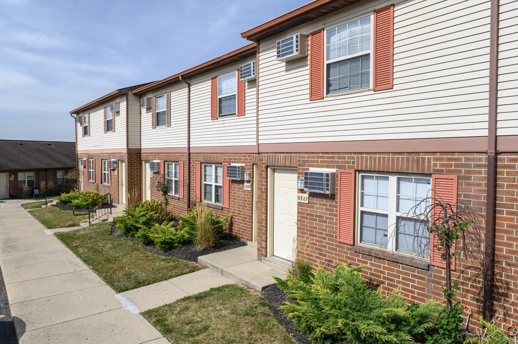 a brick and white building with a sidewalk in front of it