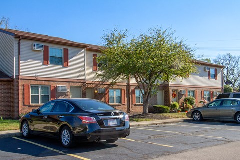 an apartment building with cars parked in a parking lot