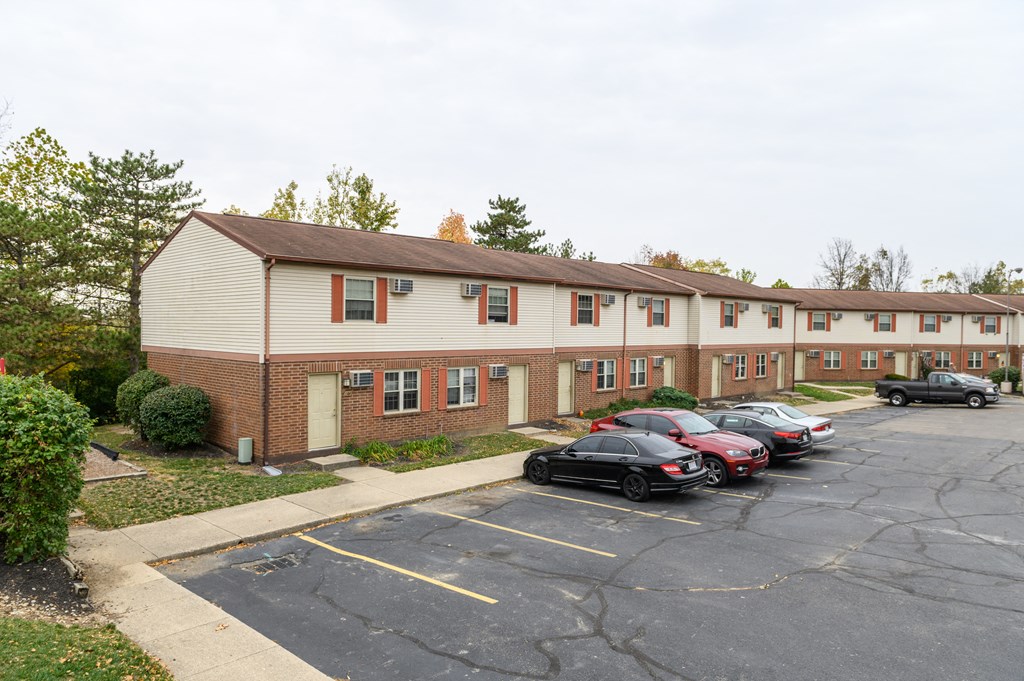 an apartment building with cars parked in a parking lot