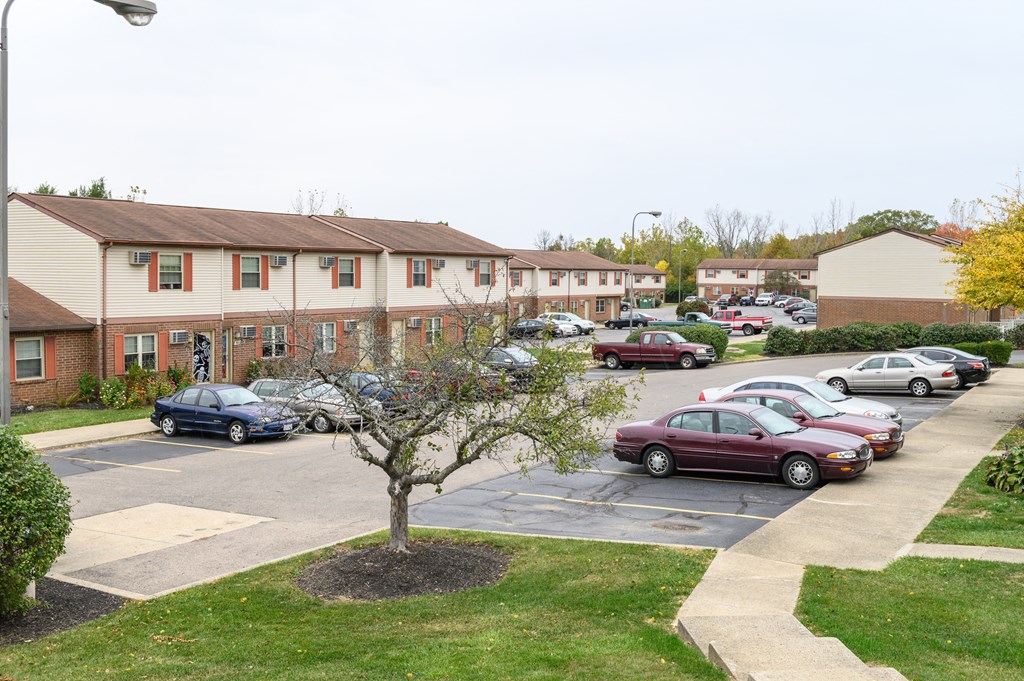 a parking lot filled with cars in front of an apartment building