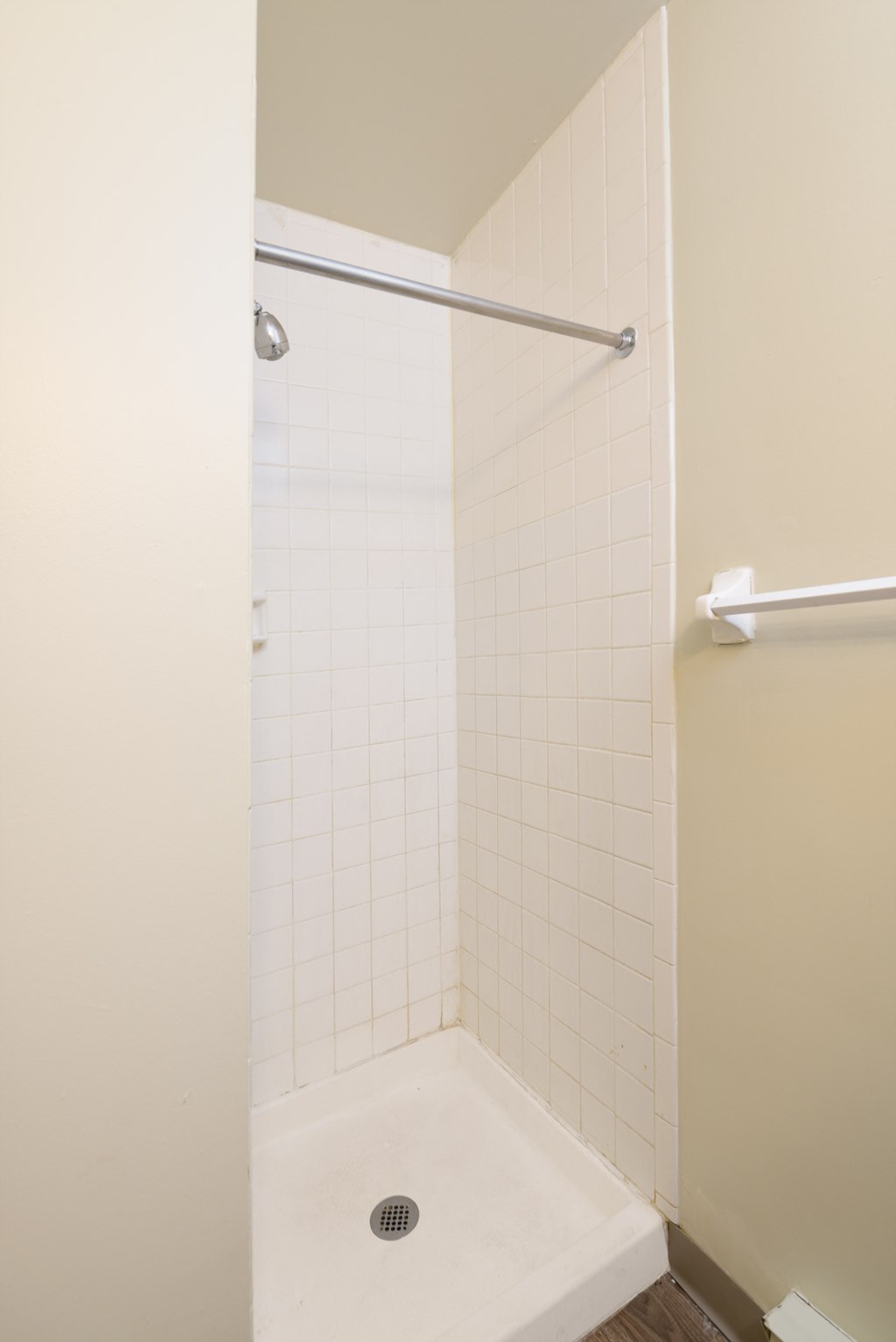 a shower with white tile and a shower curtain