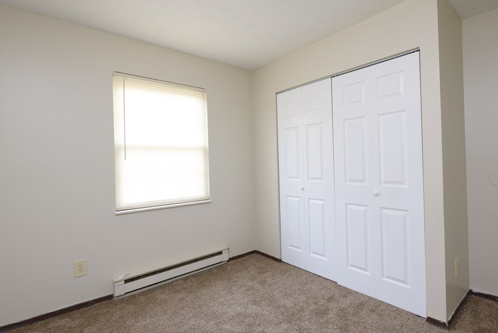 an empty bedroom with two doors and a window