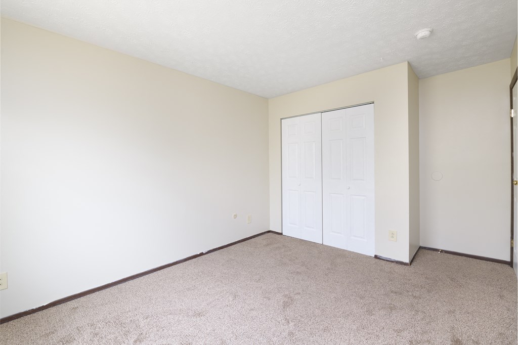 an empty living room with white walls and a door to a closet