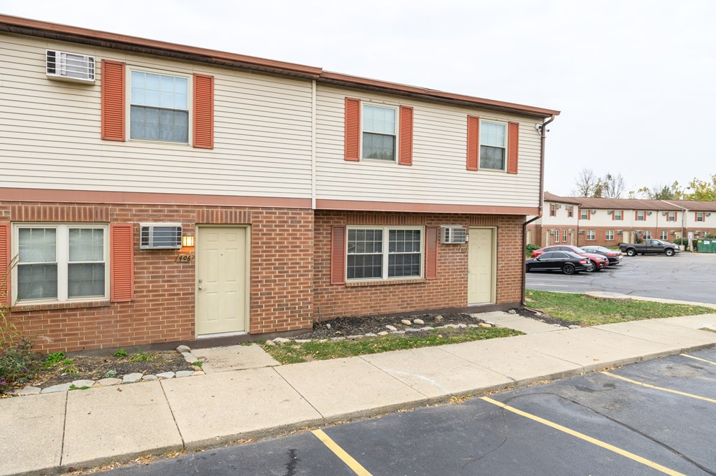 the front of a brick building with two doors and a sidewalk