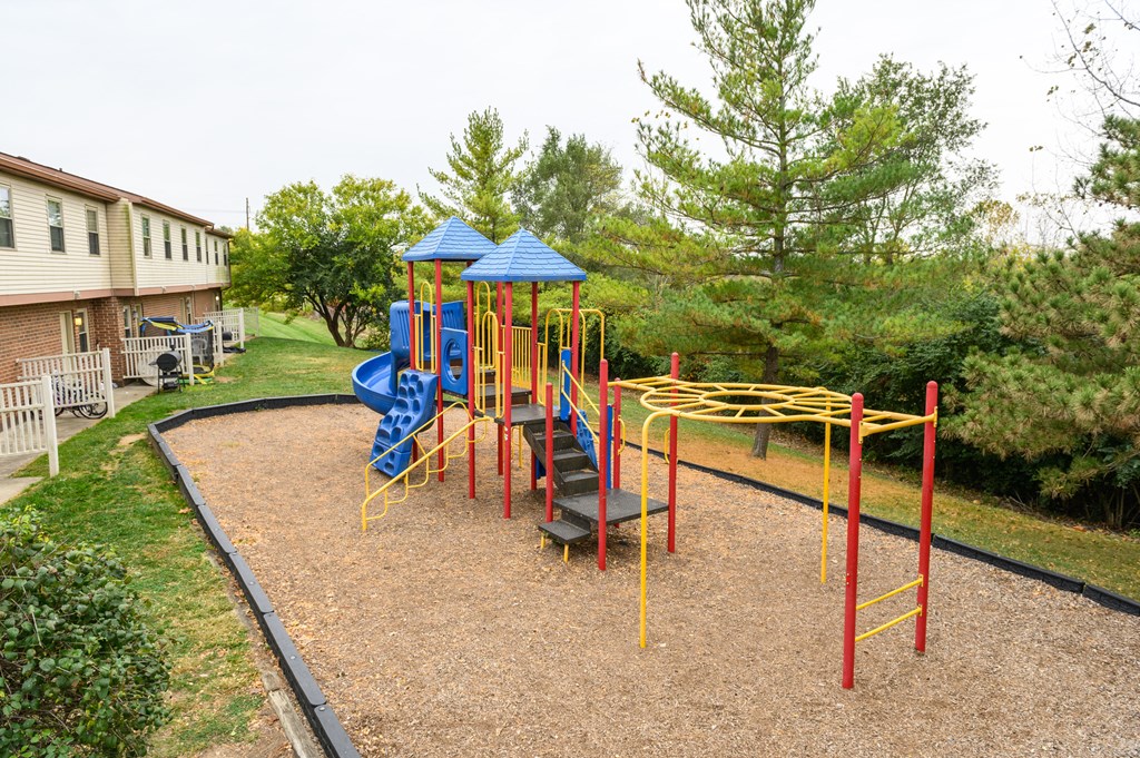 a playground in a yard with a blue and yellow swing set