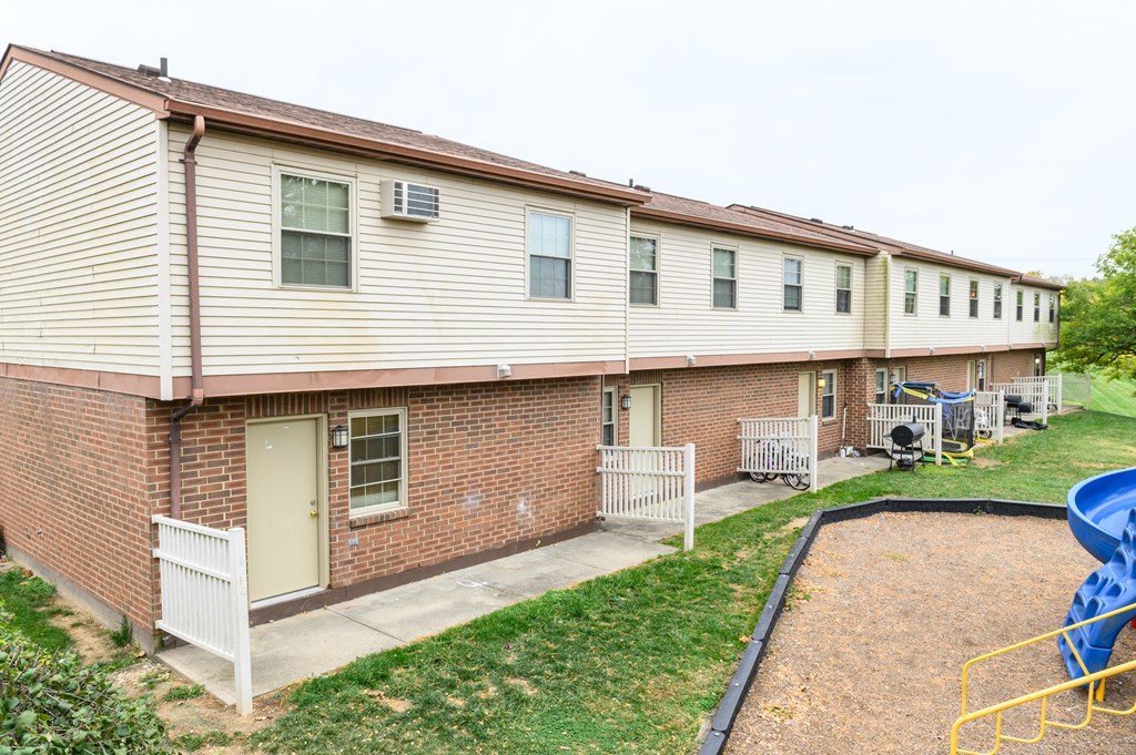 the back of a brick building with a playground and a yard
