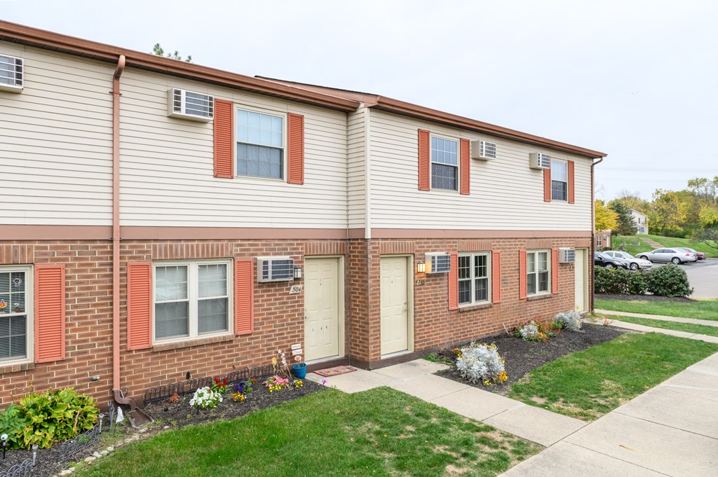 the front of a brick and white building with a sidewalk