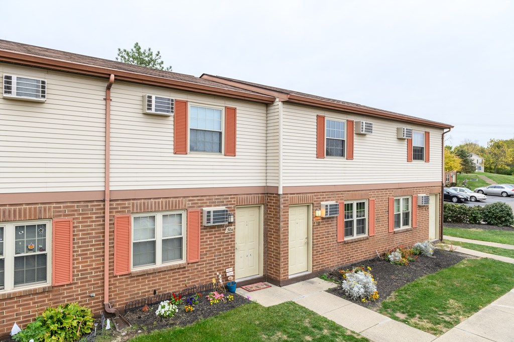 the front of an apartment building with a sidewalk and grass