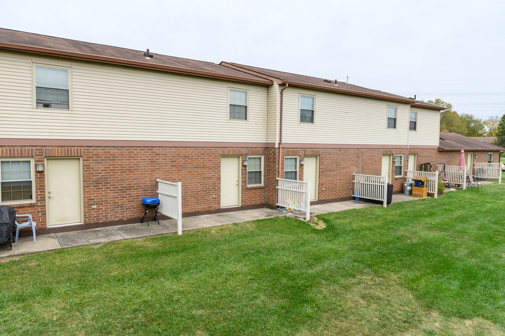 the front of a brick building with a yard and a porch