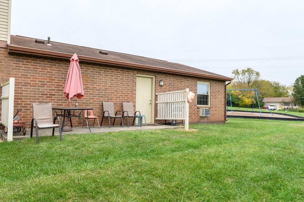 the backyard of a brick house with an umbrella and patio furniture