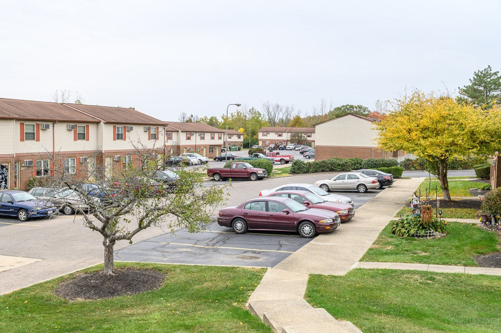 a parking lot with cars in front of an apartment complex