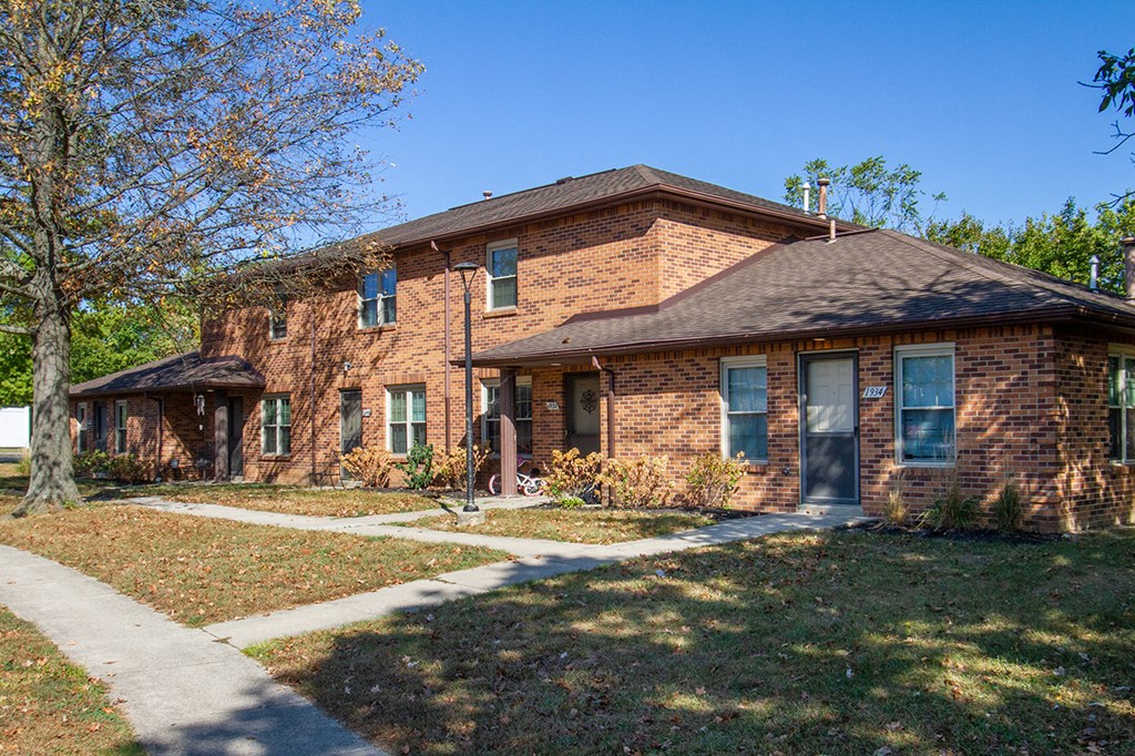 a brick house with a sidewalk in front of it