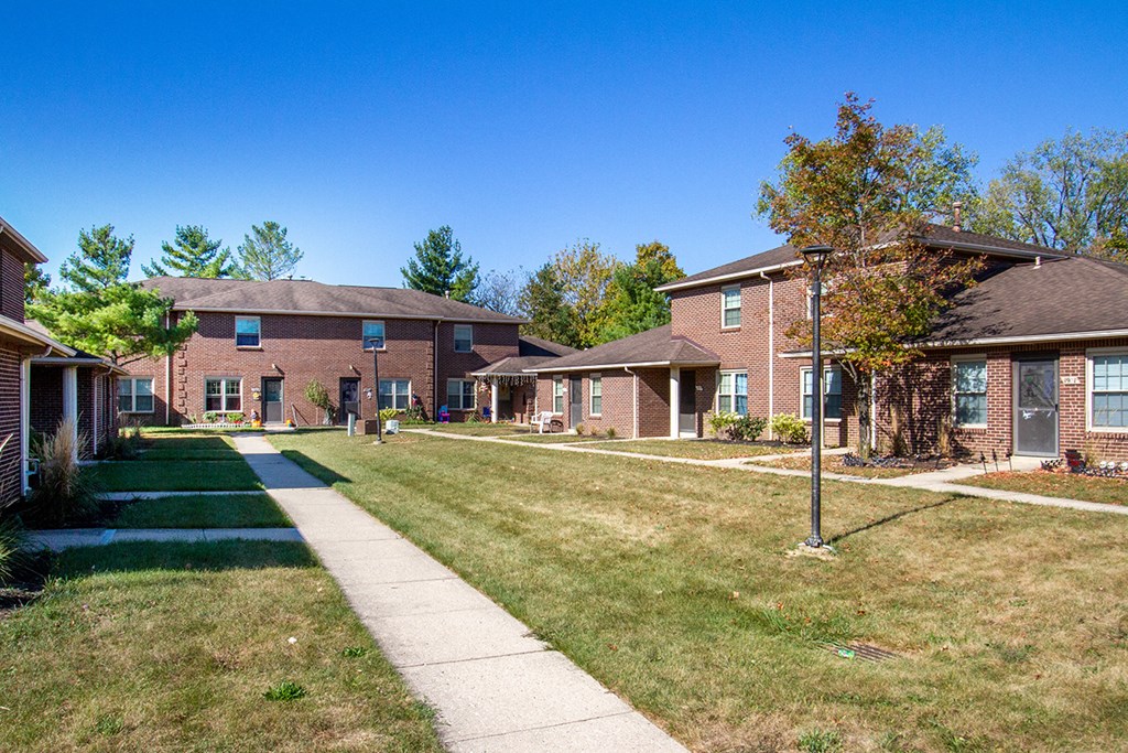 a row of brick houses with a sidewalk and grass