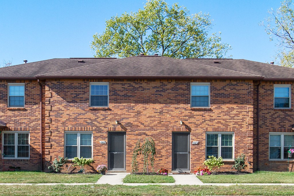 a brick house with three doors and a lawn